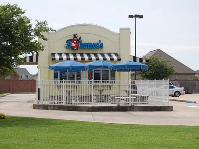 Colorful ice cream shop with outdoor seating area, featuring display case of frozen custard flavors and specialty toppings.