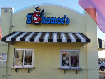 Colorful ice cream shop with outdoor seating area where customers enjoy frozen custard treats while some patrons bring...