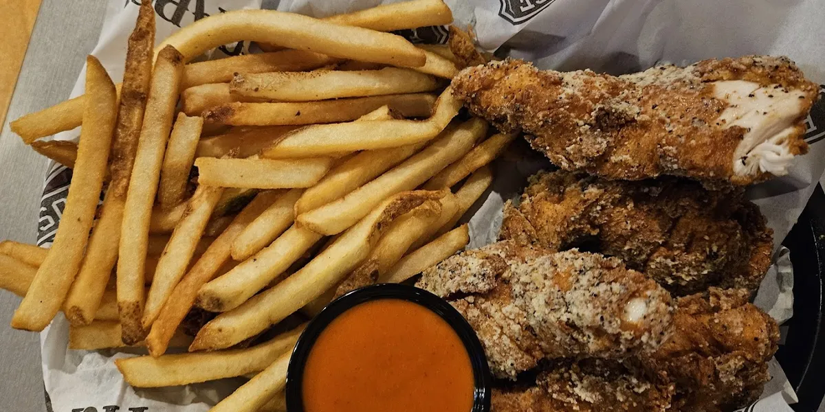 Bright, cafeteria-style bar & grill with casual seating, bustling lunch crowd, and beer towers visible at the...