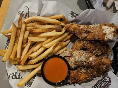 Bright, cafeteria-style bar & grill with casual seating, bustling lunch crowd, and beer towers visible at the...