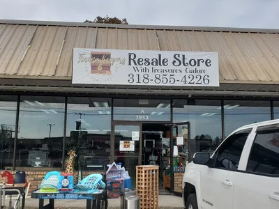 Neatly organized consignment store with rows of furniture, headboards, and display cases of name-brand shoes in a bright,...