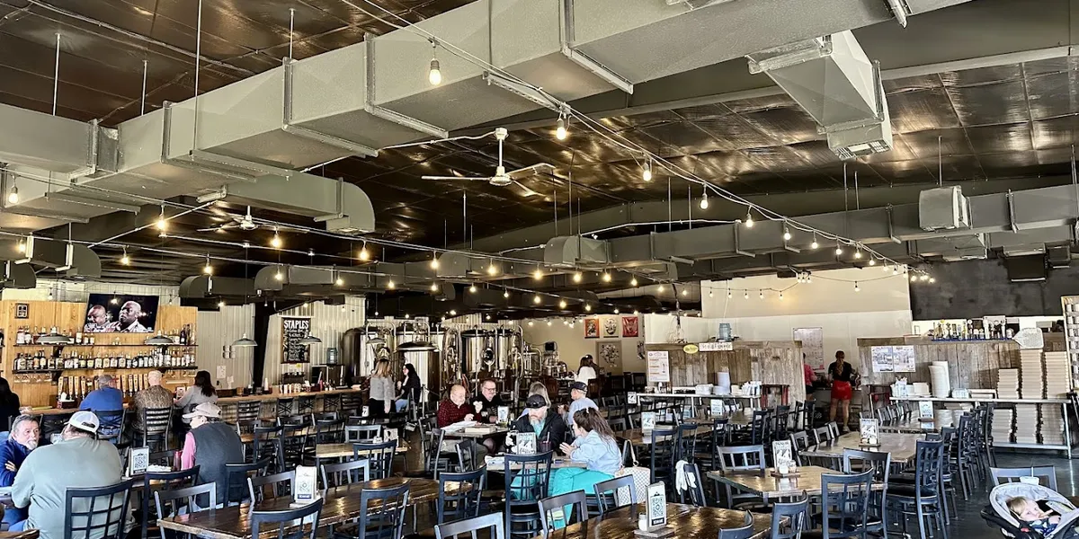 Spacious beer garden at Flying Heart Brewing with outdoor seating, taps pouring house-crafted beers, and wood-fired...