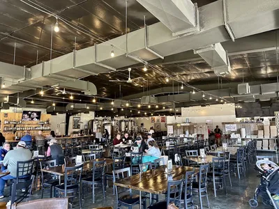 Spacious beer garden at Flying Heart Brewing with outdoor seating, taps pouring house-crafted beers, and wood-fired...