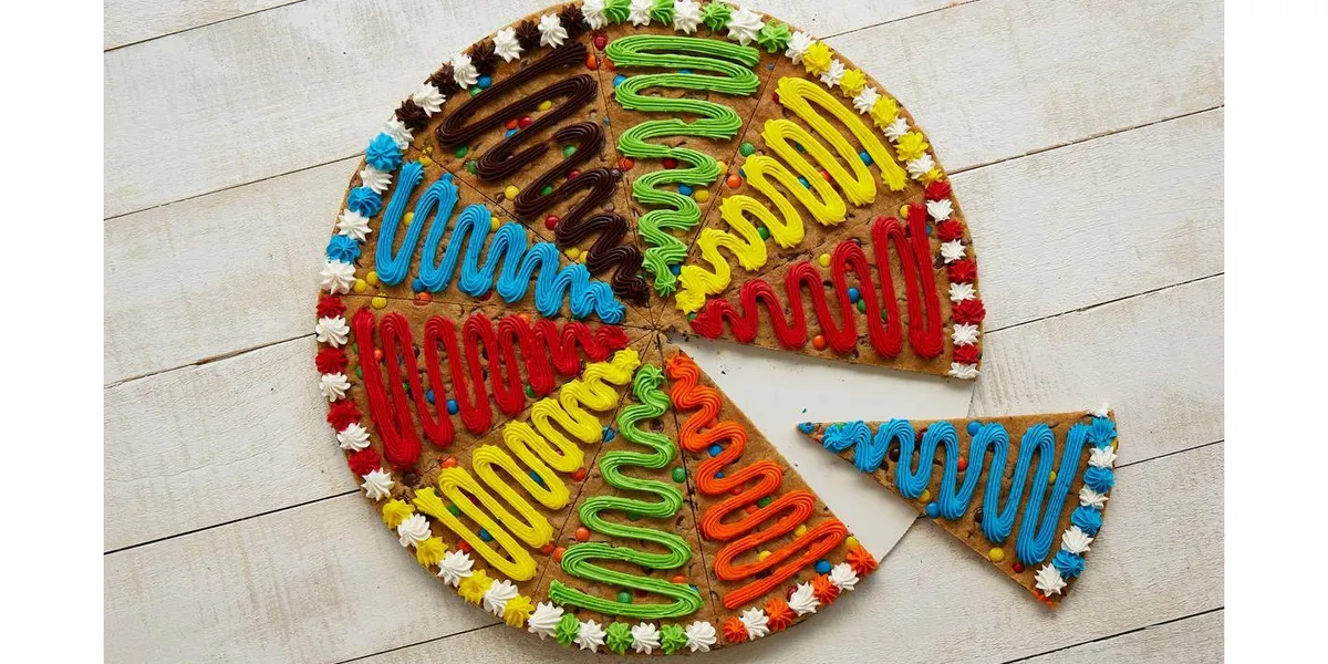 Glass counter displaying colorfully decorated cookies and custom cookie cakes with detailed designs in a bright mall...