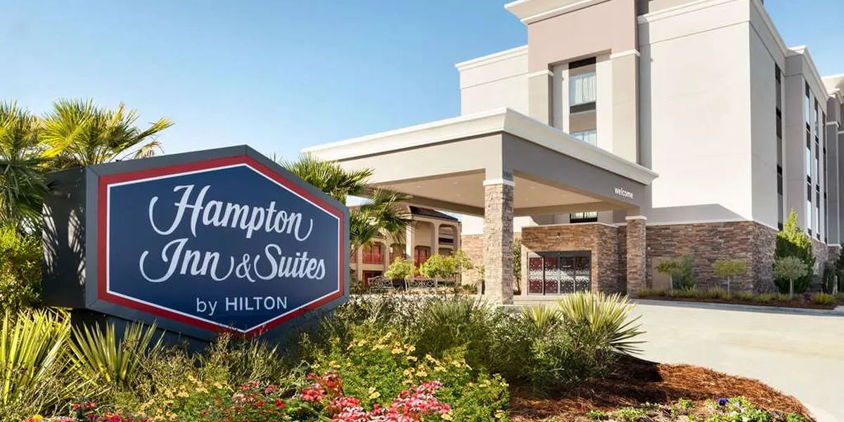 Modern hotel exterior with ample parking, featuring bright lobby with coffee station and spacious breakfast area with...