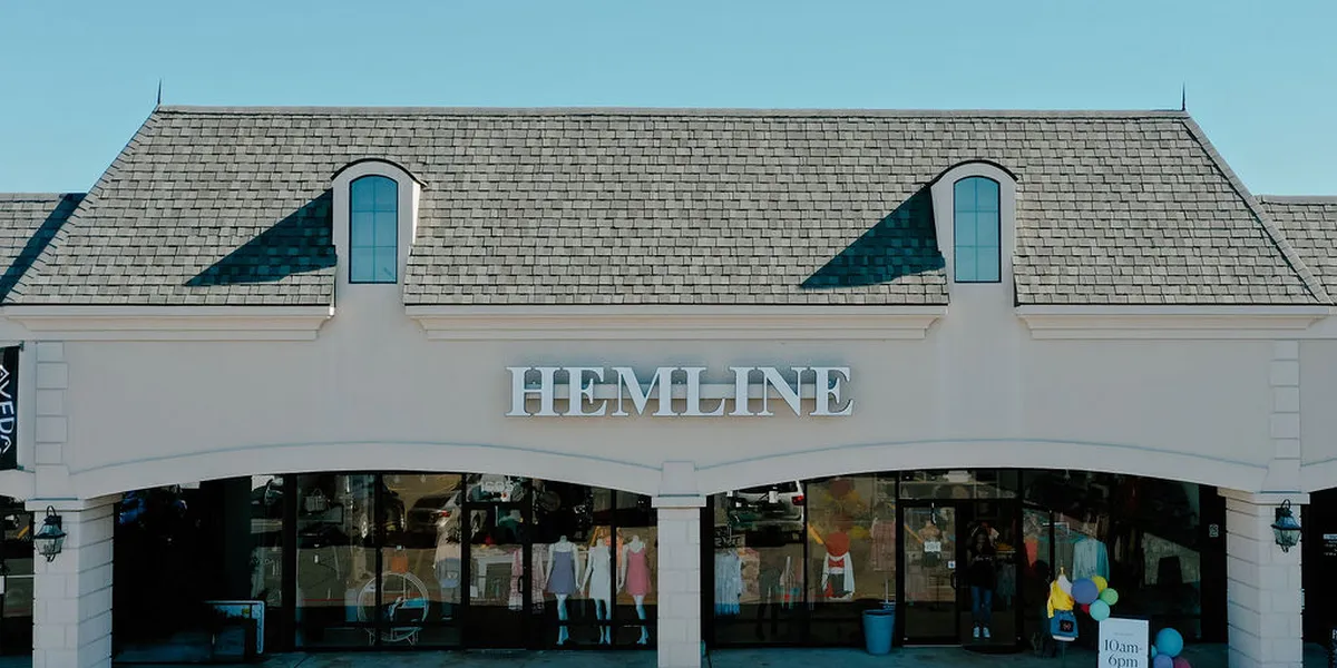 Bright, well-organized women's boutique with elegantly displayed clothing racks, accessory displays, and spacious fitting...