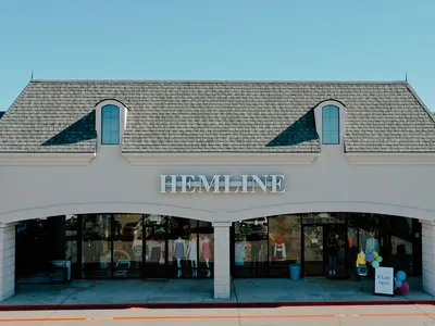 Bright, well-organized women's boutique with elegantly displayed clothing racks, accessory displays, and spacious fitting...