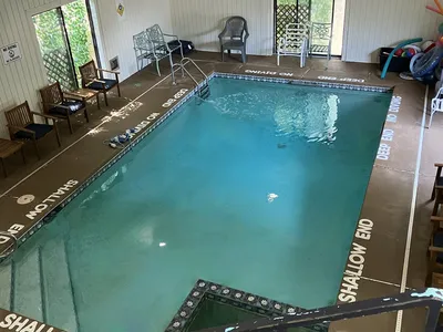Spacious indoor swimming pool with adjacent hot tub, surrounded by pool chairs and colorful floaties in a private,...
