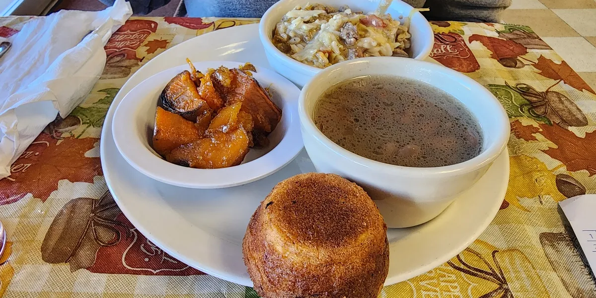 Cozy family-style restaurant with tables of diners enjoying traditional plate lunches and homemade sides in a casual,...