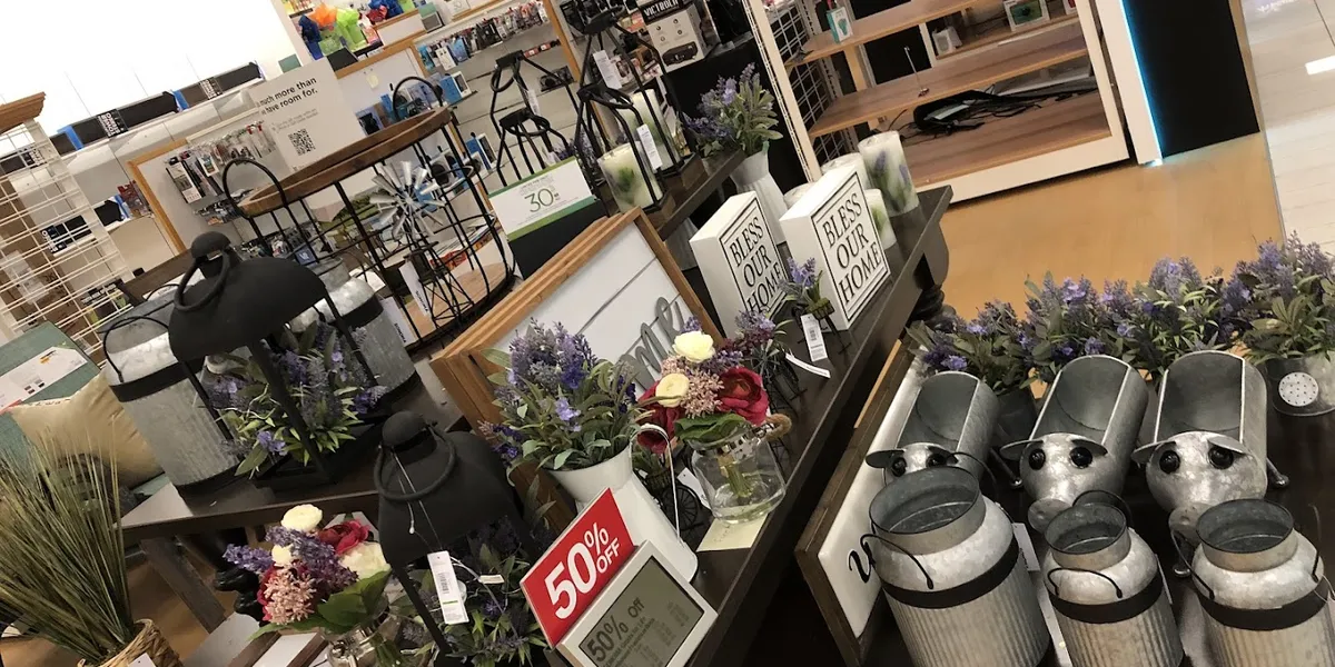Spacious, well-organized department store with neatly arranged clothing racks and household sections under bright lighting.