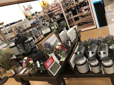 Spacious, well-organized department store with neatly arranged clothing racks and household sections under bright lighting.