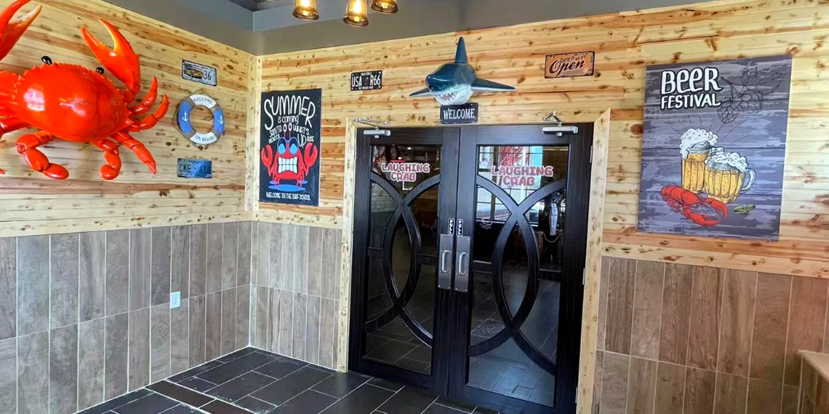 Bustling seafood restaurant with tables of steaming crab legs and seafood boils, served in bags with various sauce options.