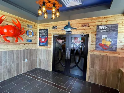 Bustling seafood restaurant with tables of steaming crab legs and seafood boils, served in bags with various sauce options.