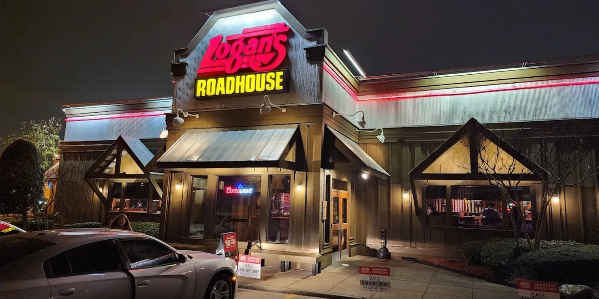 Rustic roadhouse-style restaurant with wooden tables, peanut shells on floor, and warm lighting highlighting their...
