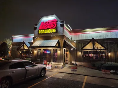 Rustic roadhouse-style restaurant with wooden tables, peanut shells on floor, and warm lighting highlighting their...