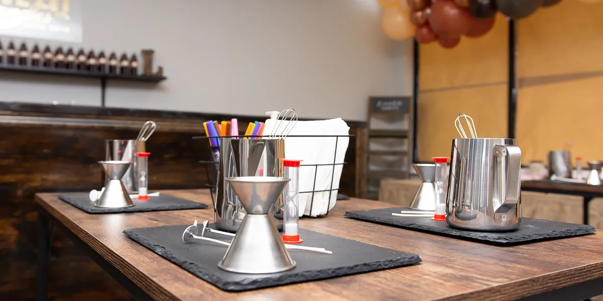 Bright candle-making studio with pouring stations, scent selection area, and casual seating for groups enjoying...