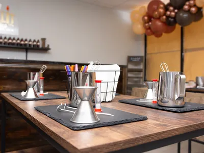 Bright candle-making studio with pouring stations, scent selection area, and casual seating for groups enjoying...