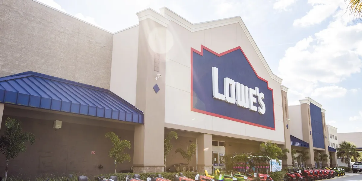 Expansive Lowe's Home Improvement warehouse with wide aisles, towering shelves of building supplies, and distinctive blue...