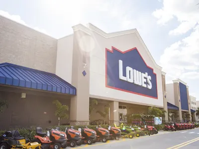 Expansive Lowe's Home Improvement warehouse with wide aisles, towering shelves of building supplies, and distinctive blue...