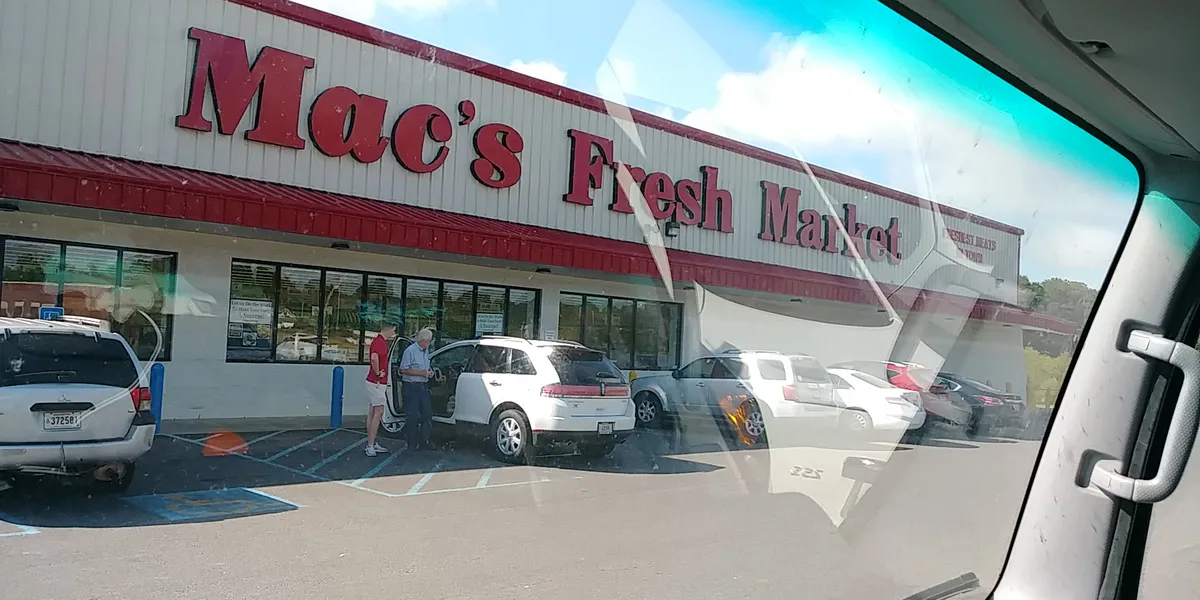 Neighborhood grocery store with well-stocked meat counter, wide aisles, and shopping carts lined up at checkout with 10%...