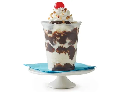 Bright ice cream shop with marble mixing slabs, colorful toppings display, and family-friendly outdoor seating area on...