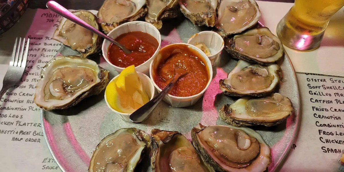 Vintage seafood tavern with outdoor seating area, bustling with locals enjoying fresh oysters and seafood platters in a...