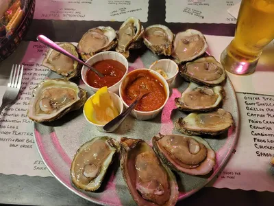 Vintage seafood tavern with outdoor seating area, bustling with locals enjoying fresh oysters and seafood platters in a...