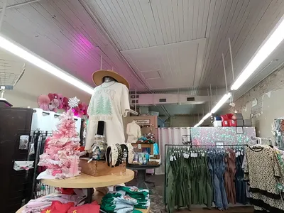 Bright, homey boutique with neatly arranged clothing displays and monogramming samples, creating a warm atmosphere for...