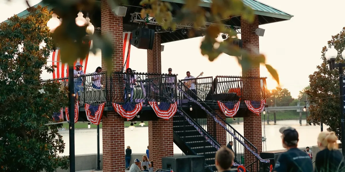Compact boardwalk along the Ouachita River with vendor stalls, offering scenic water views and gathering spaces for families.