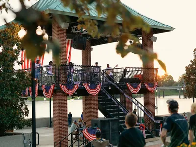 Compact boardwalk along the Ouachita River with vendor stalls, offering scenic water views and gathering spaces for families.