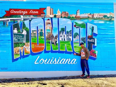 Colorful mural painted on the side of a building in downtown Monroe, situated near the river with pedestrians viewing the...