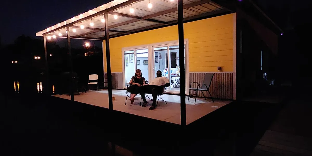 Serene waterfront view of Moon Lake showing floating cabins with fishing decks, kayaks at the shoreline, and tree-lined...