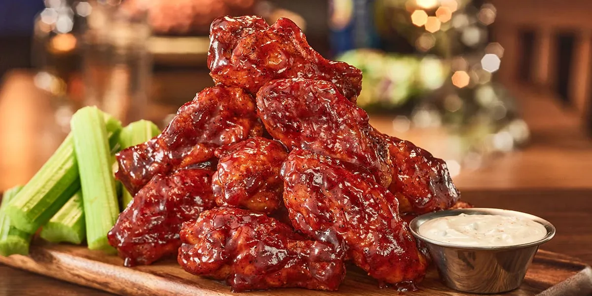 Outback Steakhouse exterior with parking lot for curbside pickup, featuring rustic Australian-themed signage on...