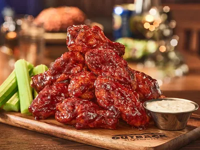 Outback Steakhouse exterior with parking lot for curbside pickup, featuring rustic Australian-themed signage on...