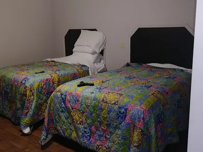 Modest roadside motel with parking lot along Louisville Ave, featuring simple exterior with row of numbered doors and...