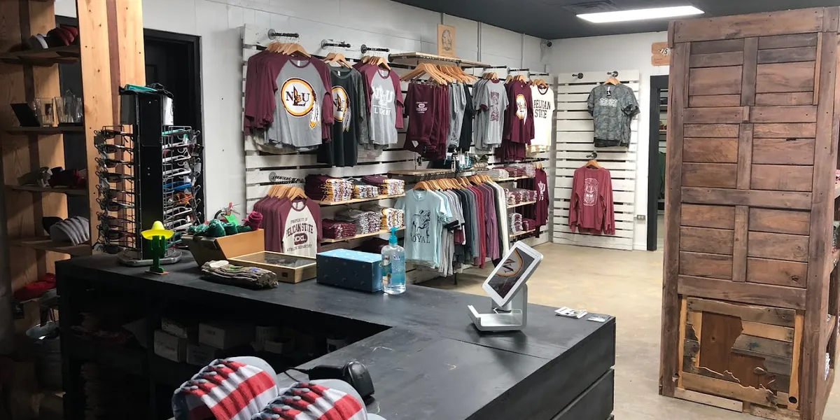 Retail space showcasing racks of custom-printed apparel with local designs and corporate uniform samples on display at...