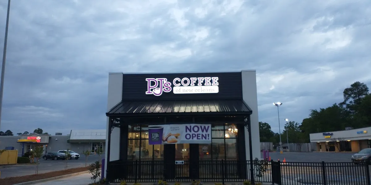 Cozy coffee shop with indoor and outdoor seating areas where customers enjoy beignets and coffee drinks in a laid-back...