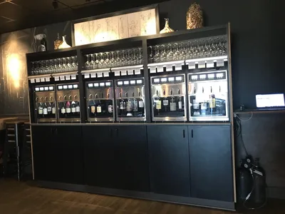 Elegant bar interior with extensive wine display, outdoor seating area with TVs, and sophisticated yet comfortable...