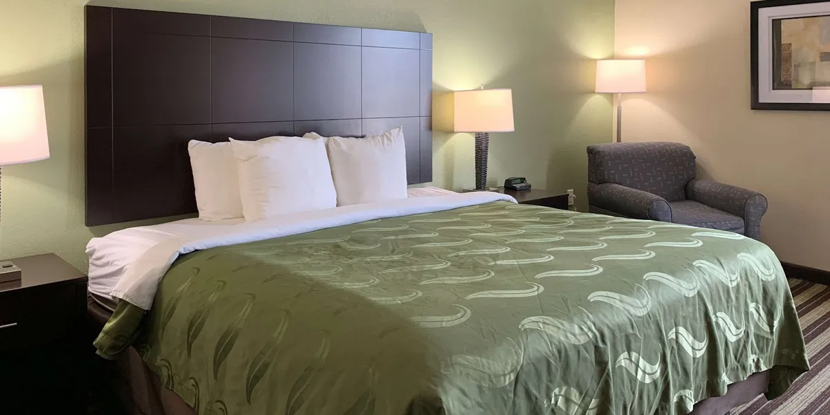 Roadside Quality Inn & Suites featuring outdoor pool area, parking lot, and standard two-story hotel exterior with room...