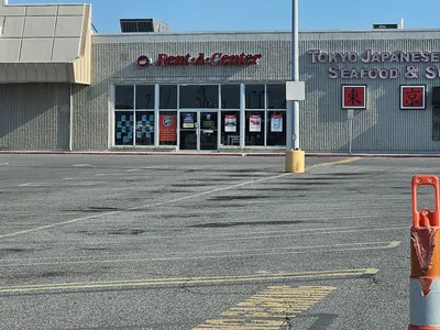 Organized showroom displaying furniture and household items available for rent, with clean aisles and product displays in...