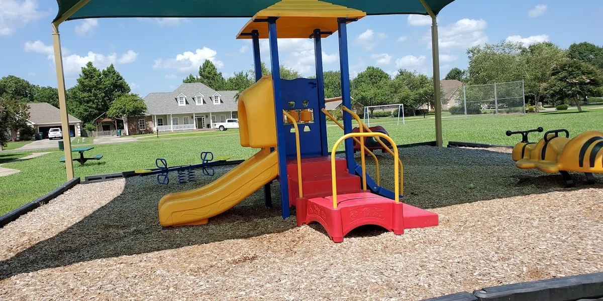 Small neighborhood playground with children's equipment surrounded by clean picnic areas and green space in a residential...
