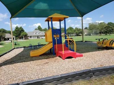 Small neighborhood playground with children's equipment surrounded by clean picnic areas and green space in a residential...