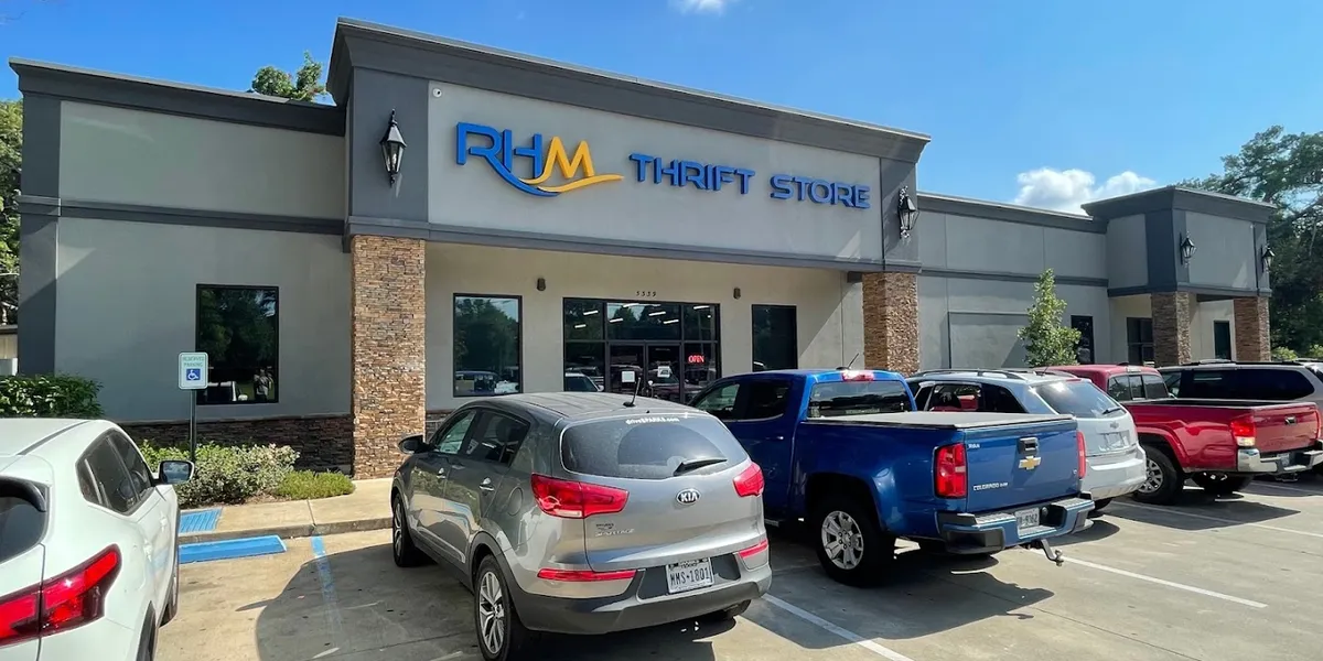 Neat, organized thrift store with clearly marked sections for furniture, clothing, and housewares, featuring bulk-donated...