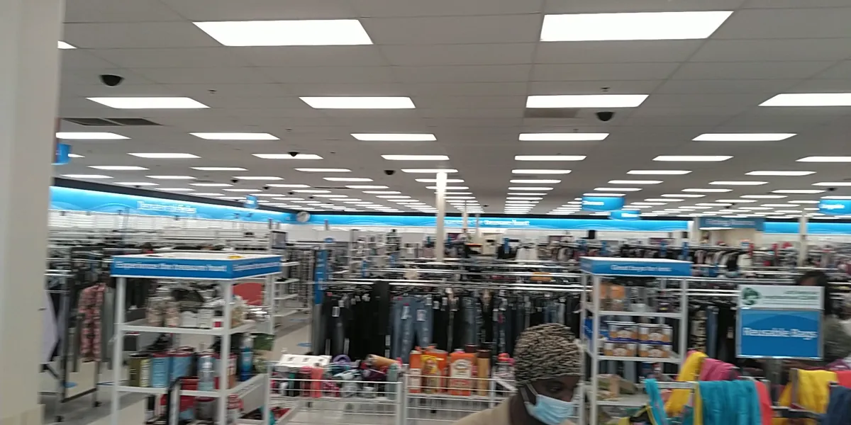 Spacious discount retail floor with racks of clothing organized by category, featuring prominent dress section and...