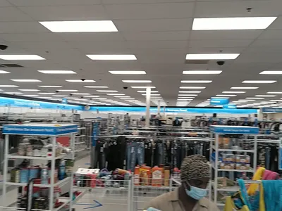 Spacious discount retail floor with racks of clothing organized by category, featuring prominent dress section and...