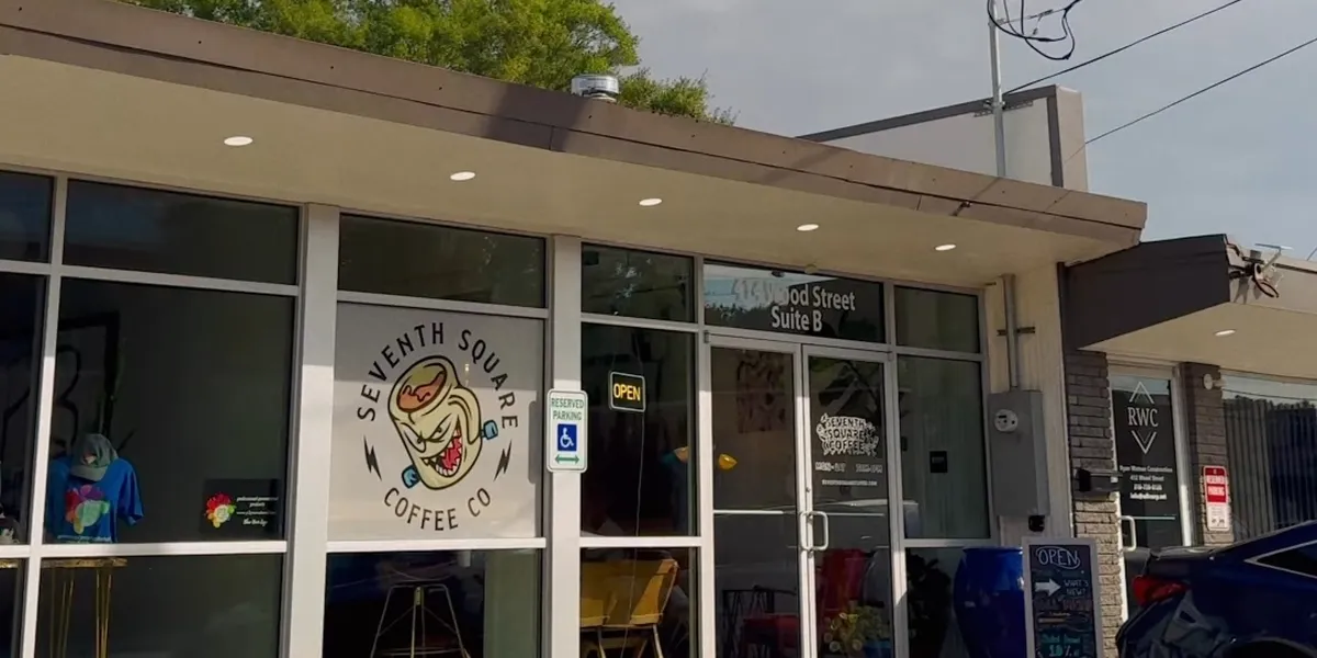 Cozy coffee shop with mixed seating arrangements - booths, couches, and bar stools - showcasing local art amid a bustling...