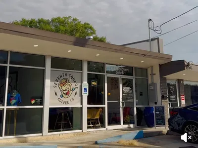 Cozy coffee shop with mixed seating arrangements - booths, couches, and bar stools - showcasing local art amid a bustling...