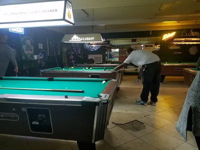 Spacious interior of Shananigans bar featuring multiple pool tables, pinball machines, and a rustic, lived-in atmosphere...