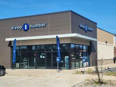 Spacious Sleep Number showroom displaying various adjustable mattress models with testing stations and digital comfort...