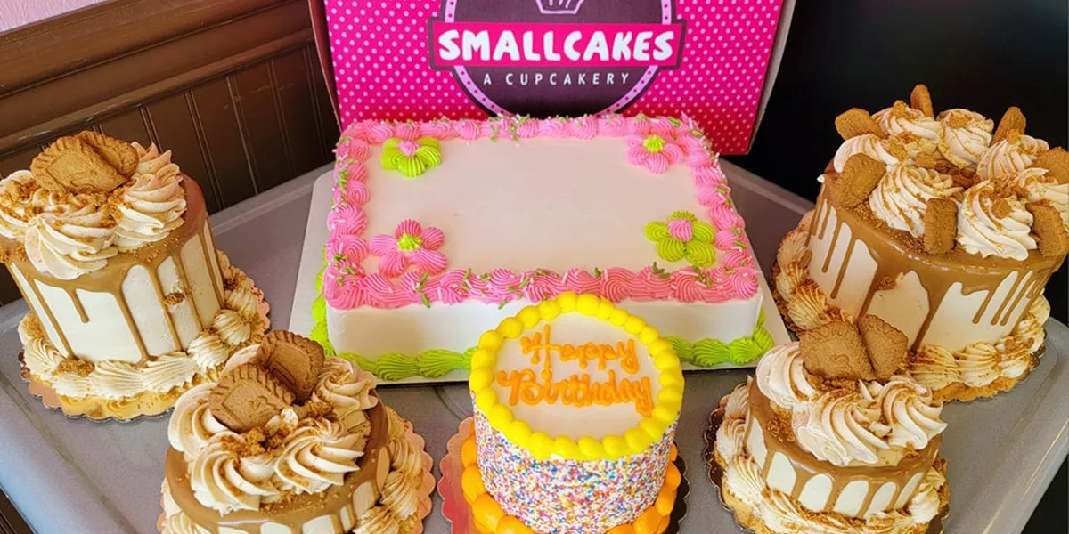 Cozy cupcake shop with glass display counter showcasing decorated cupcakes, small seating area, and signature pink packaging.